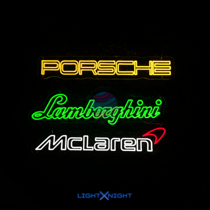 Neon signs of Porsche, Lamborghini, and McLaren logos on a black background.